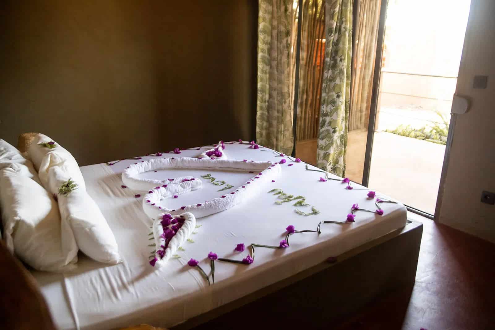 Cama decorada com flores e porta aberta para o terraço do Cajou Lodge