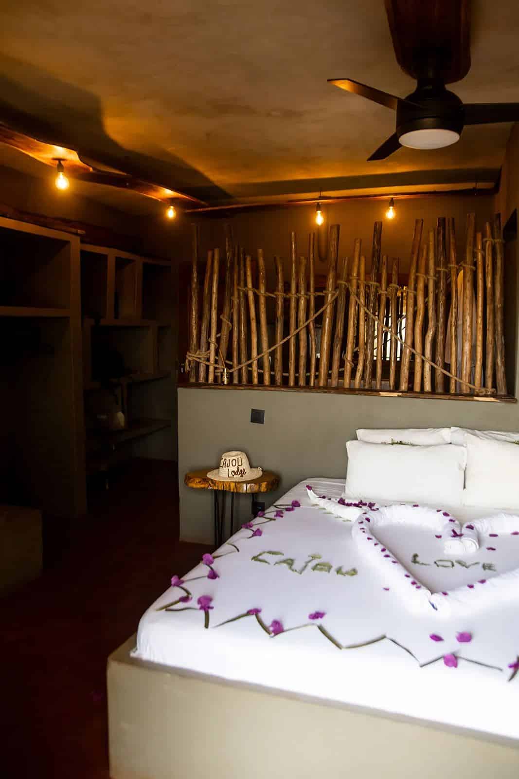 Quartos do Cajou Lodge em Bubaque: cama branca, teto de madeira e ventoinha